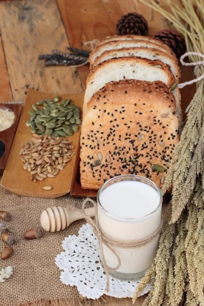 A teljes kiőrlésű gabonafélék, barna kenyér szeletelt és tej. — Stock Fotó
