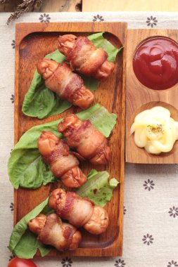 Lezzetli domuz yağında sarılı ızgara sosis.