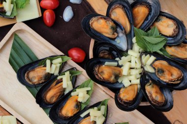 Midye fırında, peynir serpin lezzetlidir.