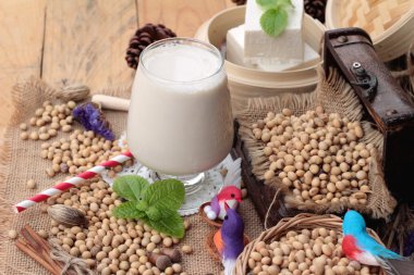 Soya sütü ve soya fasulyesi ahşap arka plan üzerinde.
