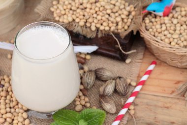 Soya sütü ve soya fasulyesi ahşap arka plan üzerinde.
