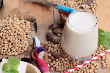 Soya sütü ve soya fasulyesi ahşap arka plan üzerinde.