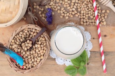 Soya sütü ve soya fasulyesi ahşap arka plan üzerinde.