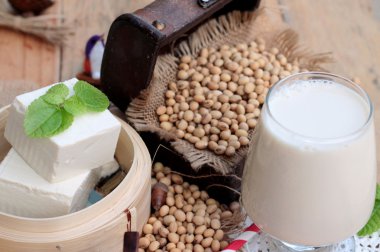 Soya sütü ve soya fasulyesi ahşap arka plan üzerinde.