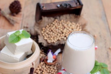 Soya sütü ve soya fasulyesi ahşap arka plan üzerinde.