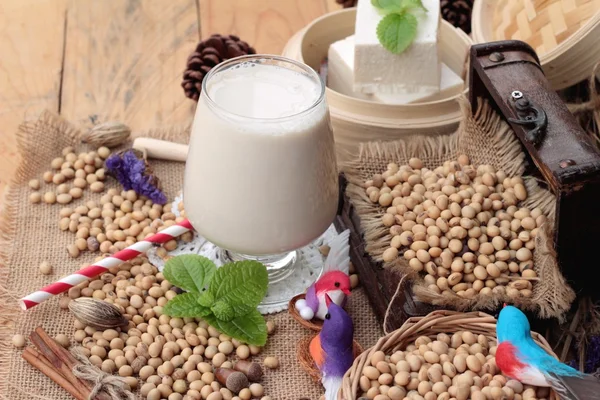 Soya sütü ve soya fasulyesi ahşap arka plan üzerinde.