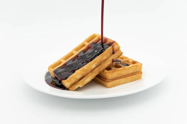 Beyaz arka planda hanımeli ya da yaban mersini şurubu dökülmüş waffle 'lar. 