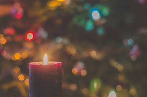 一个燃烧着蜡烛的概念 背景上的圣诞树上闪烁着亮晶晶的韧带 — 图库照片