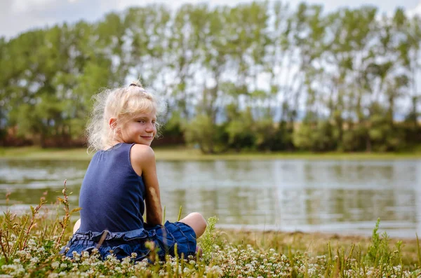 Kleines Mädchen Sitzt Auf Der Grünen Wiese Und Blickt Zum — Stockfoto