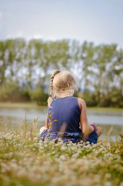 Kleines Mädchen Sitzt Auf Der Grünen Wiese Und Blickt Zum — Stockfoto