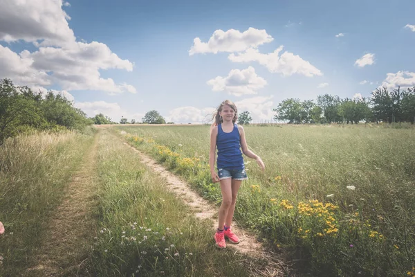Kırsal Yolda Yeşil Çayırların Arasında Yürüyen Uzun Sarı Saçlı Kız — Stok fotoğraf