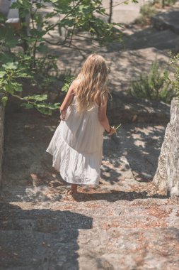 Uzun beyaz elbiseli, sağlıklı, uzun sarı saçlı güzel bir kız.