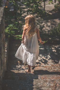 Uzun beyaz elbiseli, sağlıklı, uzun sarı saçlı güzel bir kız.