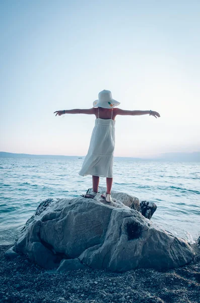 Menina Vestido Branco Chapéu Com Mãos Ascensão Rocha Pelo Mar — Fotografia de Stock