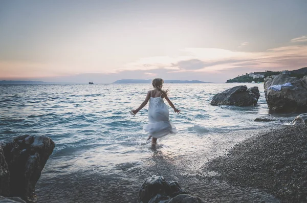 Bedårande Flicka Lång Vit Klänning Promenader Havsvatten Stranden Vid Solnedgången — Stockfoto