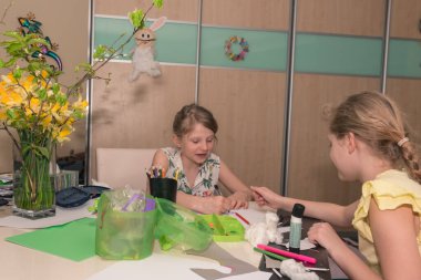 Küçük çocuklar masada oturup Paskalya 'nın yaratıcı resimlerini, el sanatlarını ve diğer çalışanları yapıyorlar.