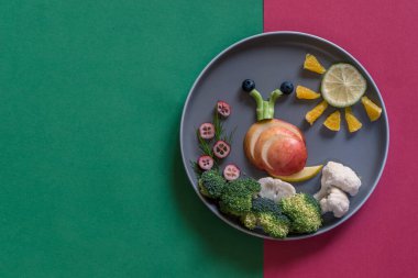 Tabaktaki mavi ve kırmızı arkaplanlı renkli sebzelerden salyangoz ve güneş şekli, boşluğu kopyala