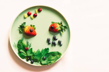 Yeşil sebze bitkisi ile balık şeklinde kırmızı çilek, deniz dünyası izole