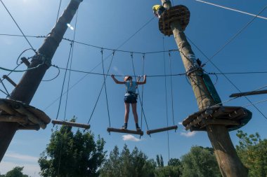 İp atlama parkında ipe tırmanan çocuk mavi gökyüzü ve günışığı arka planda