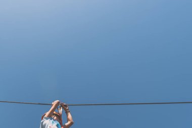 İp atlama parkında mavi arka planda ipe tırmanan çocuk.