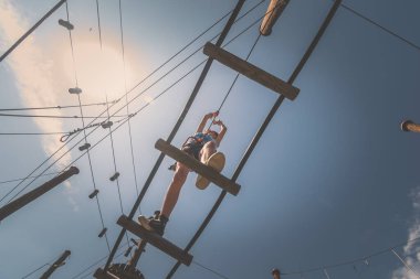 İpe tırmanan çocuk. İp çekme parkında. Açık havada güzel bir yaz gününde.