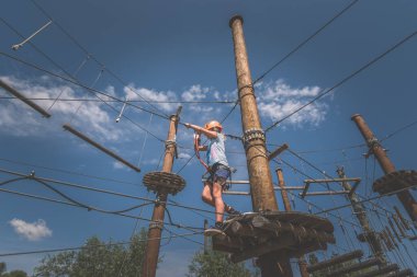 Çocuk halata tırmanıyor eğlence parkında profesyonel halat inşaatında açık havada aydınlık yaz gününde