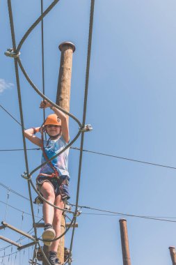 İpe tırmanan çocuk. İp çekme parkında. Açık havada güzel bir yaz gününde.
