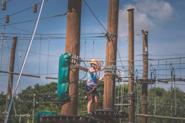 İp atlama parkında ipe tırmanan çocuk mavi gökyüzü ve günışığı arka planda