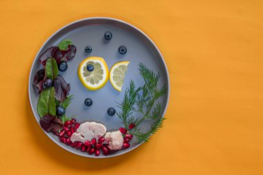 Limon dilimlerinden balık ve karnıbaharından deniz ve tabakta yaban mersini, sarı üzerine izole edilmiş kopya alanı.