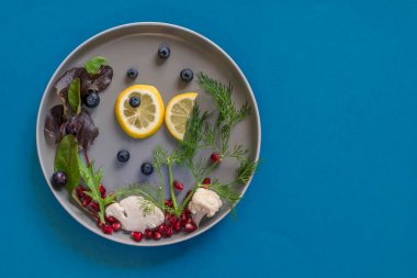 Limon dilimlerinden balık ve karnıbaharından deniz tabakta yaban mersini, mavi arkaplanda izole edilmiş kopya alanı