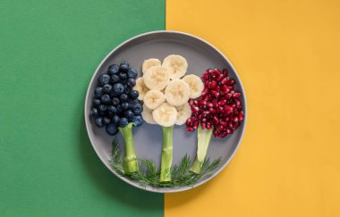 Muz, yaban mersini, nar elması, sarı ve yeşil arka planda izole edilmiş meyve ağaçları.