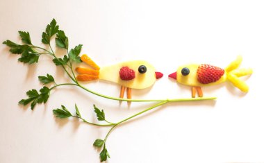 Mango, çilek, üzüm, yabanmersini ve maydanoz bitkisinden yapılmış iki kuş, sarı arka planda izole edilmiş, sevgililer günü konsepti.