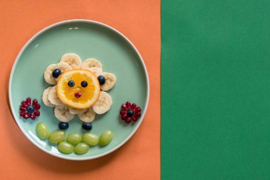 Tabakta mutlu Paskalya konsepti, yeşil tabakta vitamin dolu muz meyvesinden koyunlar, turuncu ve yeşil arka planda izole edilmiş.