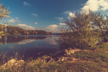 Mavi gölet ve gökyüzü yeşil ağaçlar, canlı renkler