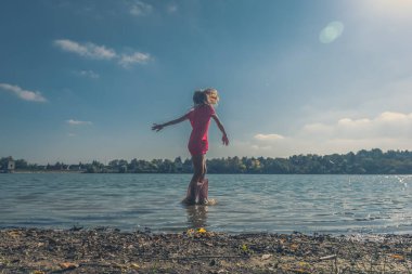 Bir çocuk suda koşarken su sıçratıyor.