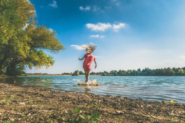Suda koşarken su sıçratan bir çocuk, özgürlük duygusu.