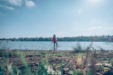 Öğleden sonra gölün kenarında yalnız bir çocuk.