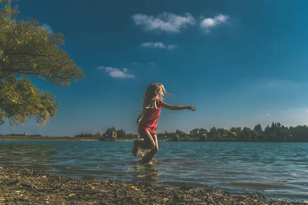 1人の子供が水の中を走りながら水を撒き散らし — ストック写真