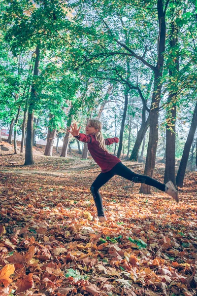 快乐的女孩在秋天的公园里在树叶间跳舞 — 图库照片