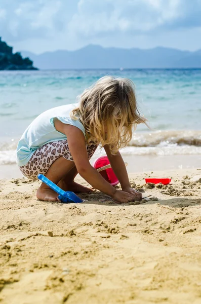 Blond flicka som leker på stranden — Stockfoto