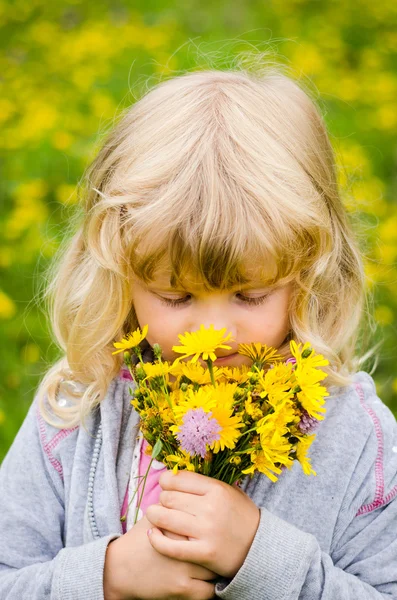 Menina loira cheirando flores — Fotografia de Stock