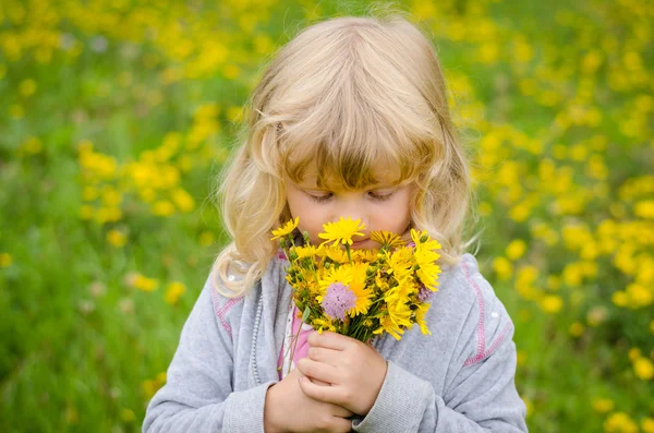 Blond girl smelling flowers — Stock Photo, Image