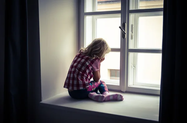 Dziewczynka, patrząc przez okno — Zdjęcie stockowe