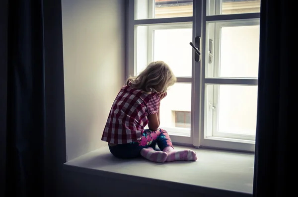 Mädchen schaut durch Fenster — Stockfoto