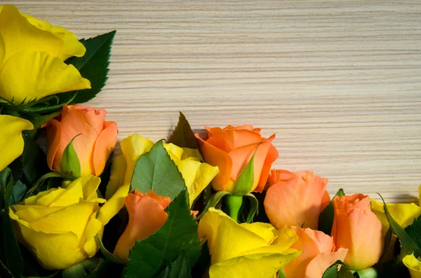 木製の背景に黄色とオレンジ色のバラ — ストック写真