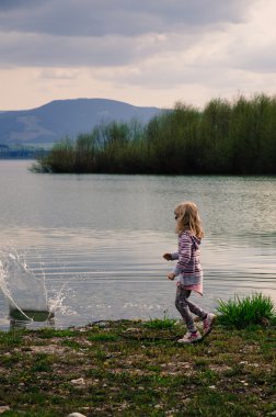 su birikintisi içine taş atan kız