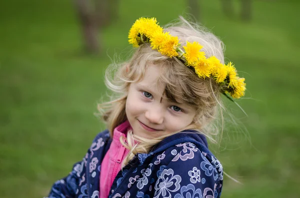 Menina bonita com flores de dente de leão sobre a cabeça — Fotografia de Stock