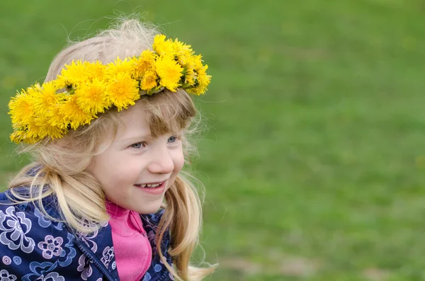 Menina bonita com flores de dente de leão sobre a cabeça — Fotografia de Stock