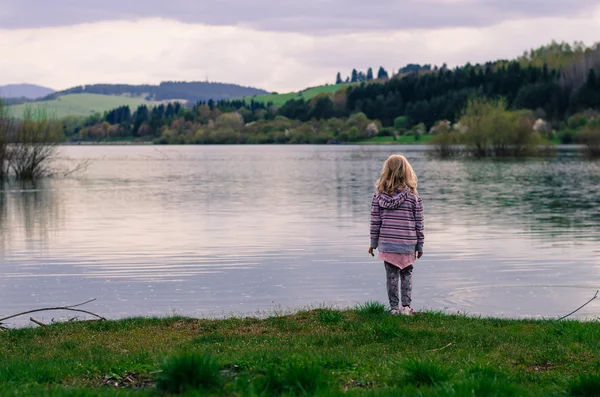 Девушка, стоящая на берегу пруда — стоковое фото
