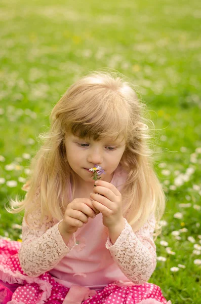 Menina loira cheirando flores — Fotografia de Stock